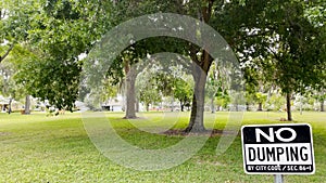 No dumping sign posted ina neighborhood park lush greenery in Florida photo