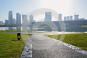 Lakeside asphalted pedestrian way on grassy lawn in summer morning