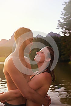 Lakeside love. an affectionate young couple hugging while swimming in a lake.