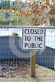 A lakeside path with a closed to the public sign