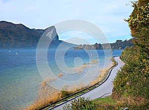 Lakeside road lake Mondsee and mountains, group of windsurfers