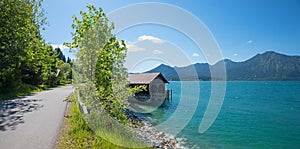 lakeside road Walchensee at springtime. shore with boathouse, mountain view