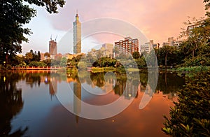 Lakeside scenery of Taipei 101 Tower among skyscrapers in Xinyi District Downtown at dusk with view of reflections on the pond