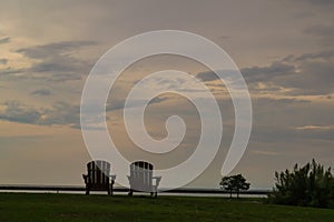 Lakeside sunset landscape with Adirondack chairs