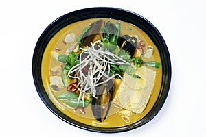 Laksa noodle soup, traditional asiatic seafood coconut flavored soup or broth with rice noodle in a bowl on white background
