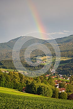 Lam, a small town in Bavaria in the summertime after a thunderstorm with a rainbow. View to mount GroÃŸer Arber with its two