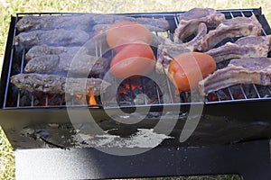 Lamb chops, kabobs and tomatoes on a charcoal grill