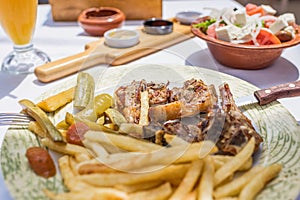 Lamb chops with vegetables and roast potatoes on a plate in a Greek restaurant or tavern.