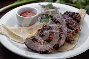 Lamb shish kebab with sauce on a white plate selective focus