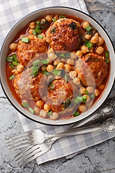 Lamb meatballs stewed with chickpeas in tomato-mint sauce close-up in a bowl. Vertical top view