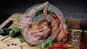 Lamb pork chops grilled with fresh salad on wooden cutting board.