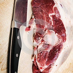 Lamb raw on a wooden board with a knife