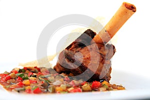 Lamb shank bone portion with vegetable cut on white background