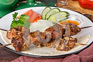 Lamb shish kebab with vegetables on a white plate