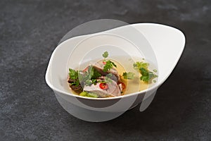 Lamb soup with chili pepper, tomatoes, parsley and beans in a white bowl
