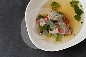 Lamb soup with chili pepper, tomatoes, parsley and beans in a white bowl