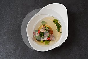 Lamb soup with chili pepper, tomatoes, parsley and beans in a white bowl