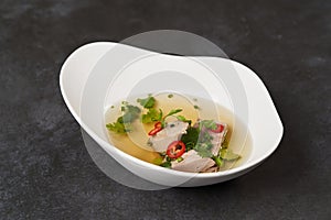 Lamb soup with chili pepper, tomatoes, parsley and beans in a white bowl