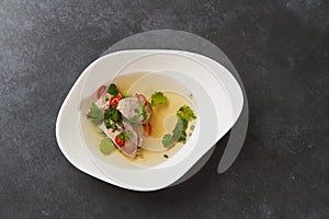 Lamb soup with chili pepper, tomatoes, parsley and beans in a white bowl