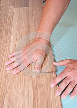 Laminate flooring installation. Men are installing plastic laminate flooring over a vapor blue underlayment