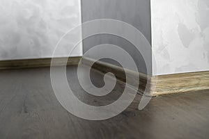 Laminate with plastic baseboard with a wooden texture. Newly installed wooden laminate flooring and baseboards in home