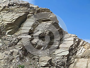 Laminated structure of mountain rock over blue sky