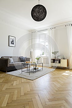 Lamp above carpet with table in spacious living room interior wi