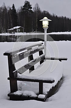 A lamp and a bench covered with snow