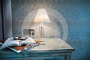 A lamp and a book on a bedside table in a hotel room.