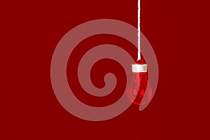 Lamp bulb hanging on the rope.  Red background. New idea concept