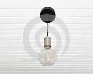 A lamp made with a tuned off light bulb. Chandelier in vintage style hanging on white wooden slatted ceiling. Lighting and
