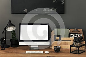 Lamp and organizer on wooden desk in grey home office interior with mockup. Real photo