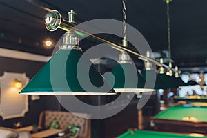 Lamp over billiards green table balls and cues.