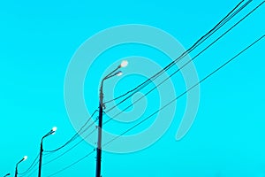 Lamp poles with power lines on a background of blue sky. Copy space