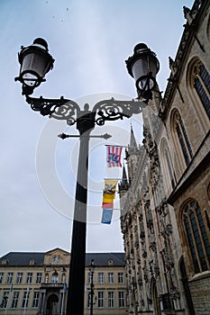 Lamp post at Burg Square during cloudy day, ancient building with flags and ornaments on the roof