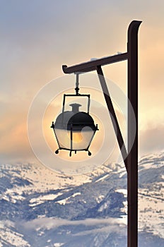 Lamp post in front of a beautiful sunset in snowy mountain