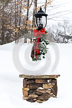 Lamp post with green and red Christmas decorations and snow