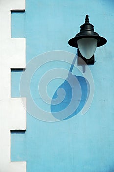 A lamp with shadow on the blue and white wall