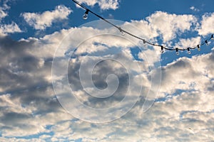 Lamp string hanging against a cloudy blue sky background