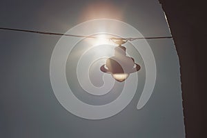 Old hanging lamp background with blue sky across a sun halo