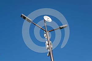 Lamppost with antenna mounted on it. Pillar against the blue sky