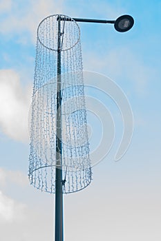 Lamppost with christmas illumination at tha day light in blue sky background