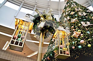 A pole with decorative chandeliers beside the Christmas tree photo
