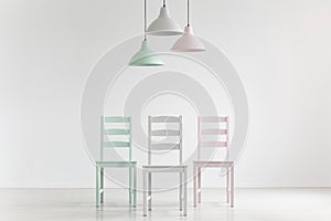 Lamps above chairs in mint, pink and grey color in white empty i