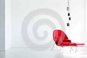 Lamps above red armchair in white living room interior with copy photo
