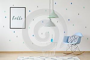 Lamps above table in kids room interior with blue rocking chair