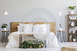 Lamps above wooden bed with white sheets in grey bedroom interio