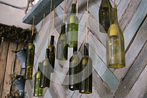 Lamps of green bottles with light bulbs hanging on the background of wooden wall