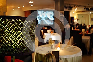 Lampshade and people sitting in restaurant, at photo