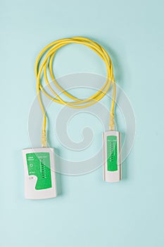 Lan tester and yellow cable on blue background.